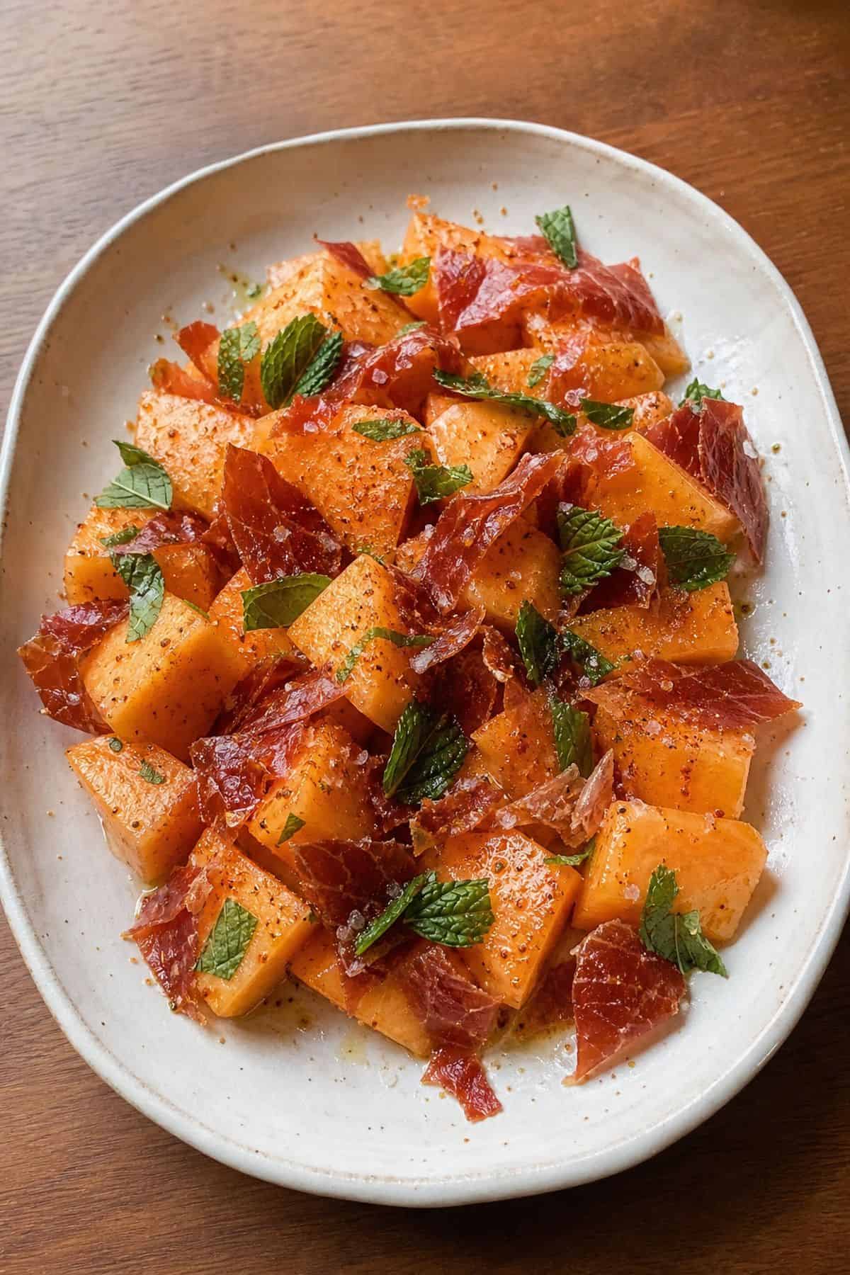 Cantaloupe salad with crispy prosciutto, mint, chili-lime seasoning, and flaky salt.
