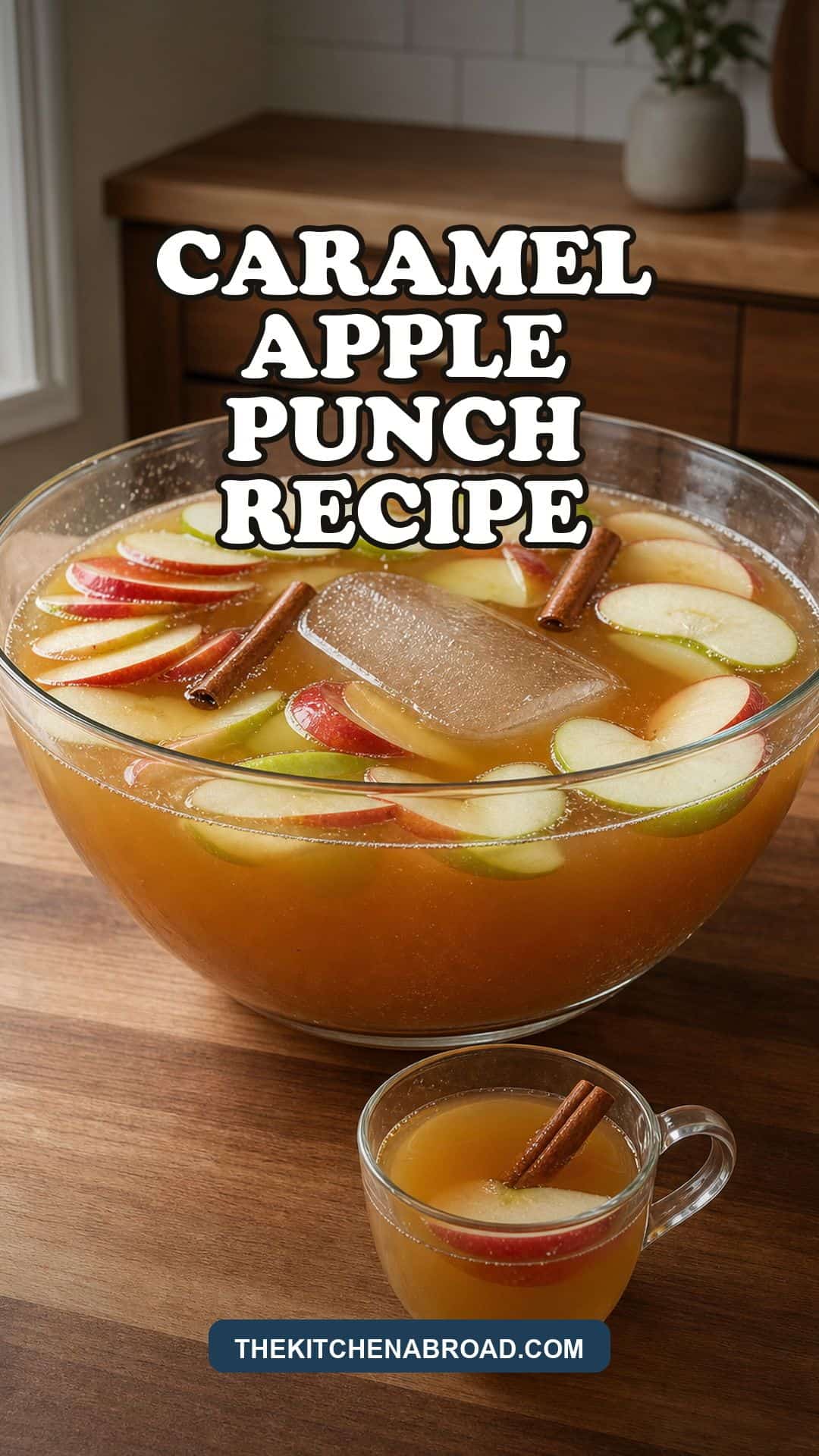 Caramel apple punch in a glass punch bowl with apple slices and cinnamon sticks