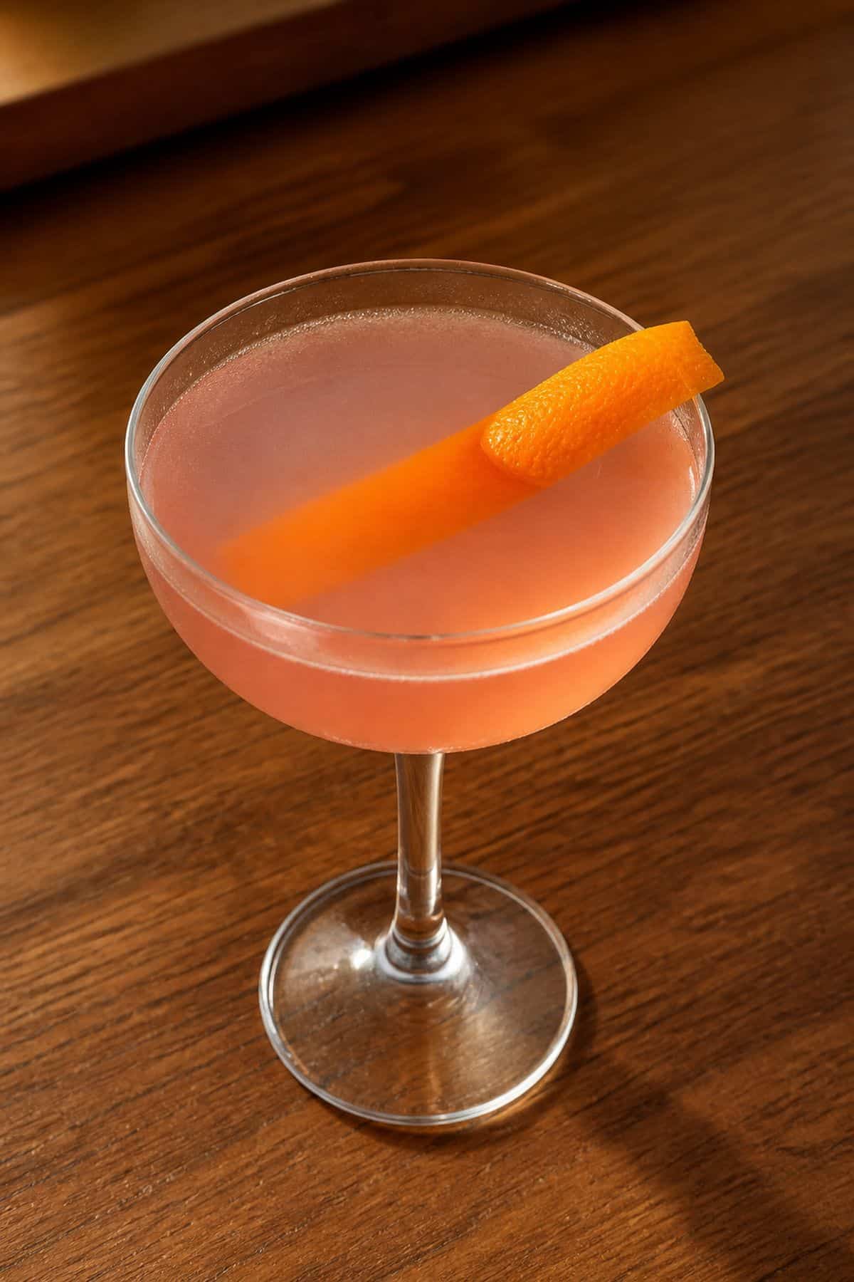 Finished Cosmopolitan cocktail with pale pink color and orange peel