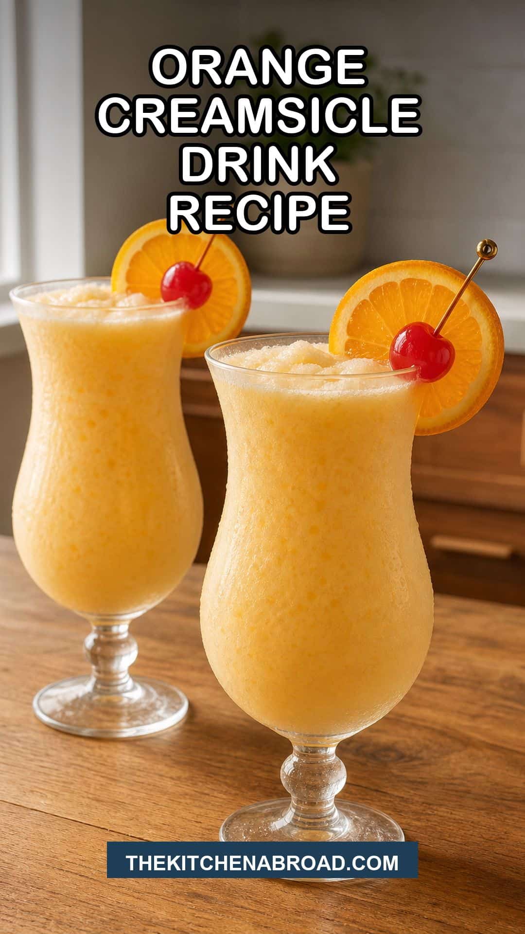 Orange creamsicle drink recipe in hurricane glasses with orange wheel and cherry garnish