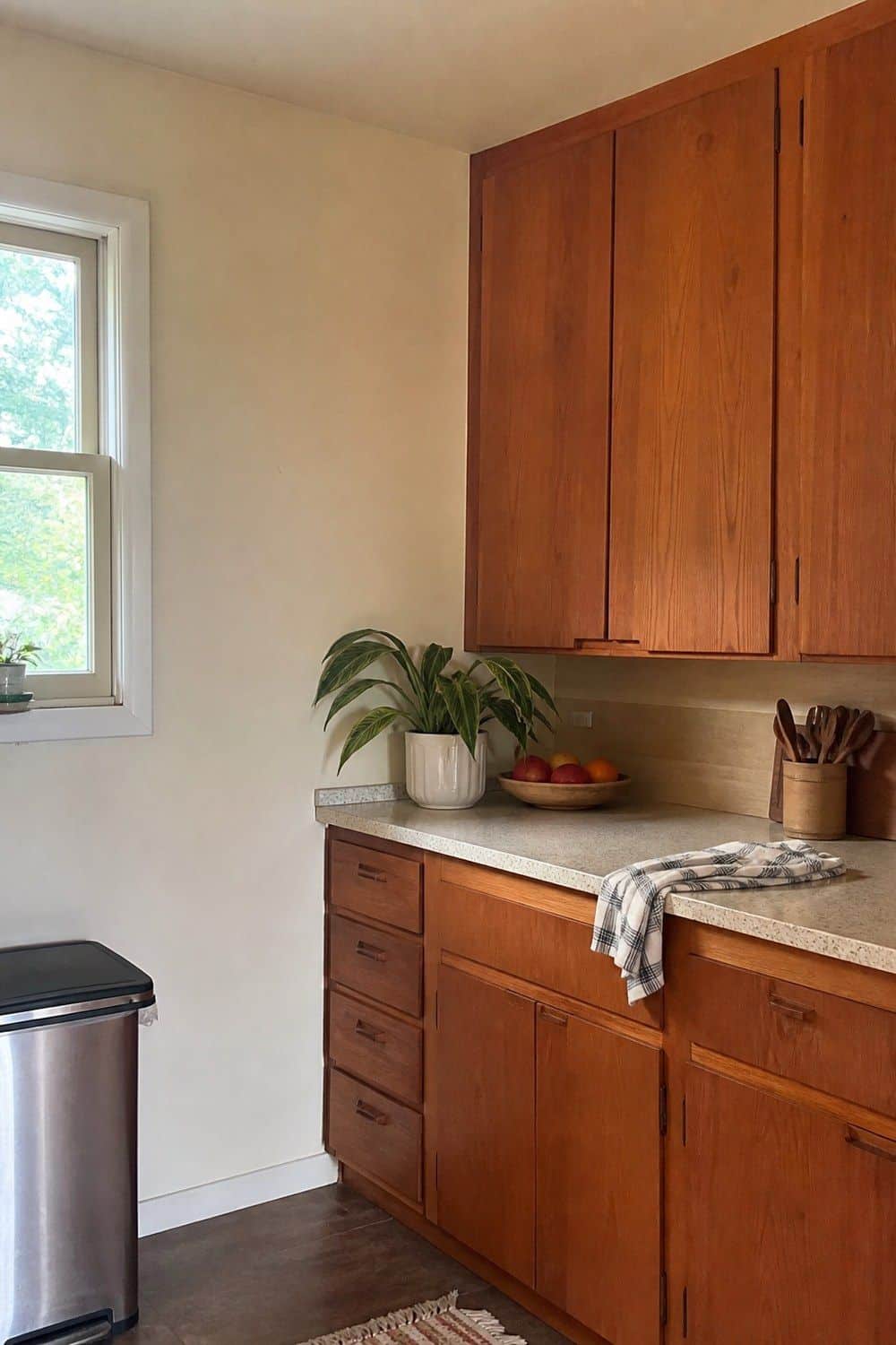 16. Warm White Walls Around Wood Cabinets in a casual mid-century modern kitchen with realistic retro warmth and everyday home details
