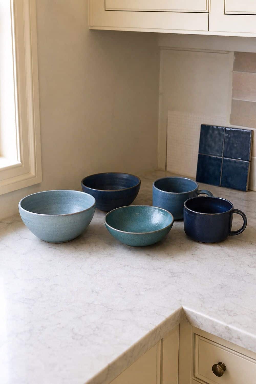 25 Blue Zellige Kitchen Ideas: Shades, Grout and Pairings Blue stoneware bowls and mugs on a kitchen counter