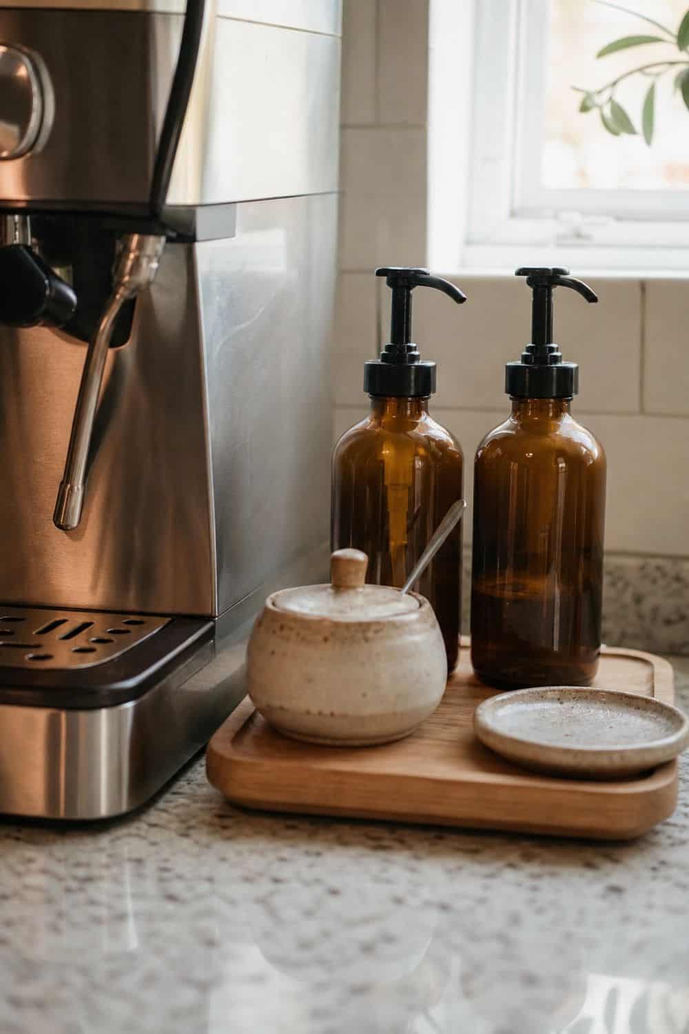 Two clean capped dispensers sit on a small tray with a controlled-pour setup and an empty drip landing area.