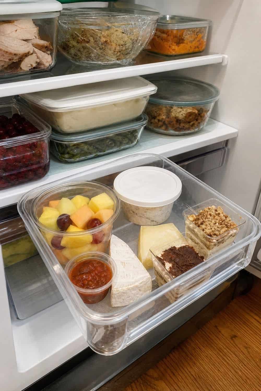 20 Holiday Fridge Ideas for Party Prep and Leftovers Holiday fridge idea showing build an eat-first bin.