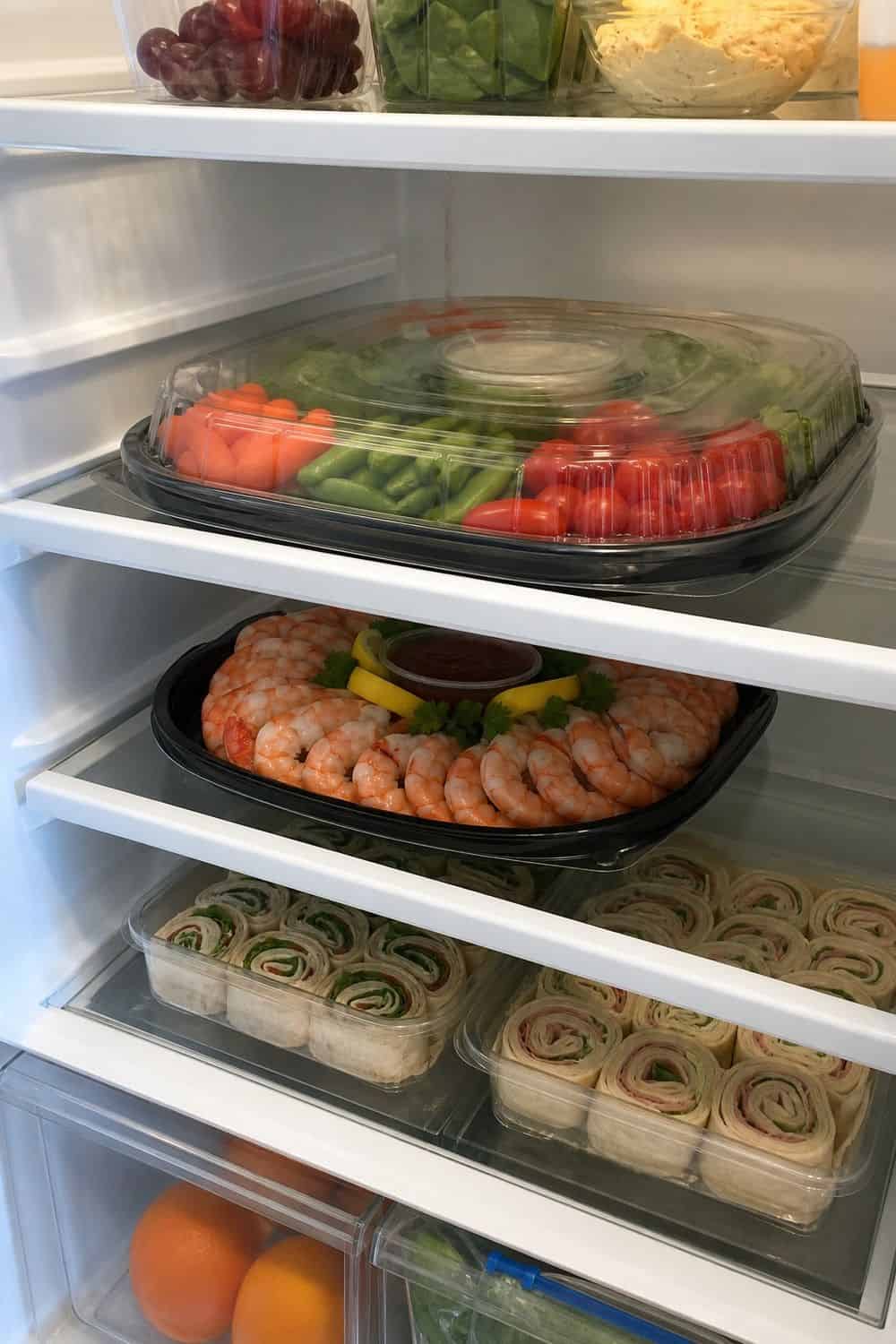 20 Holiday Fridge Ideas for Party Prep and Leftovers Holiday fridge idea showing store cold appetizer trays flat.