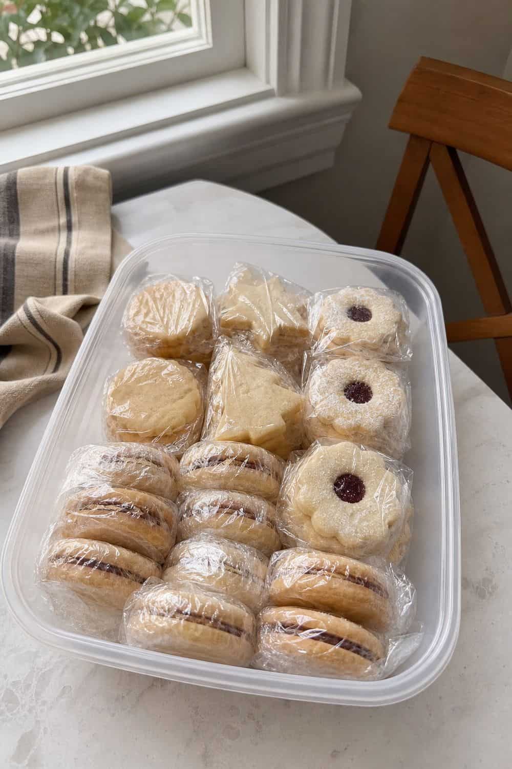 How to Store Holiday Cookies So They Stay Fresh Fragile holiday cookies wrapped in clear plastic before freezer storage.