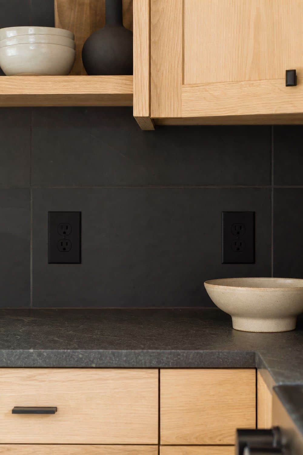 25 White Oak and Black Kitchen Ideas for High-Contrast Warmth Black Outlet Covers on a Dark Backsplash in a white oak and black kitchen